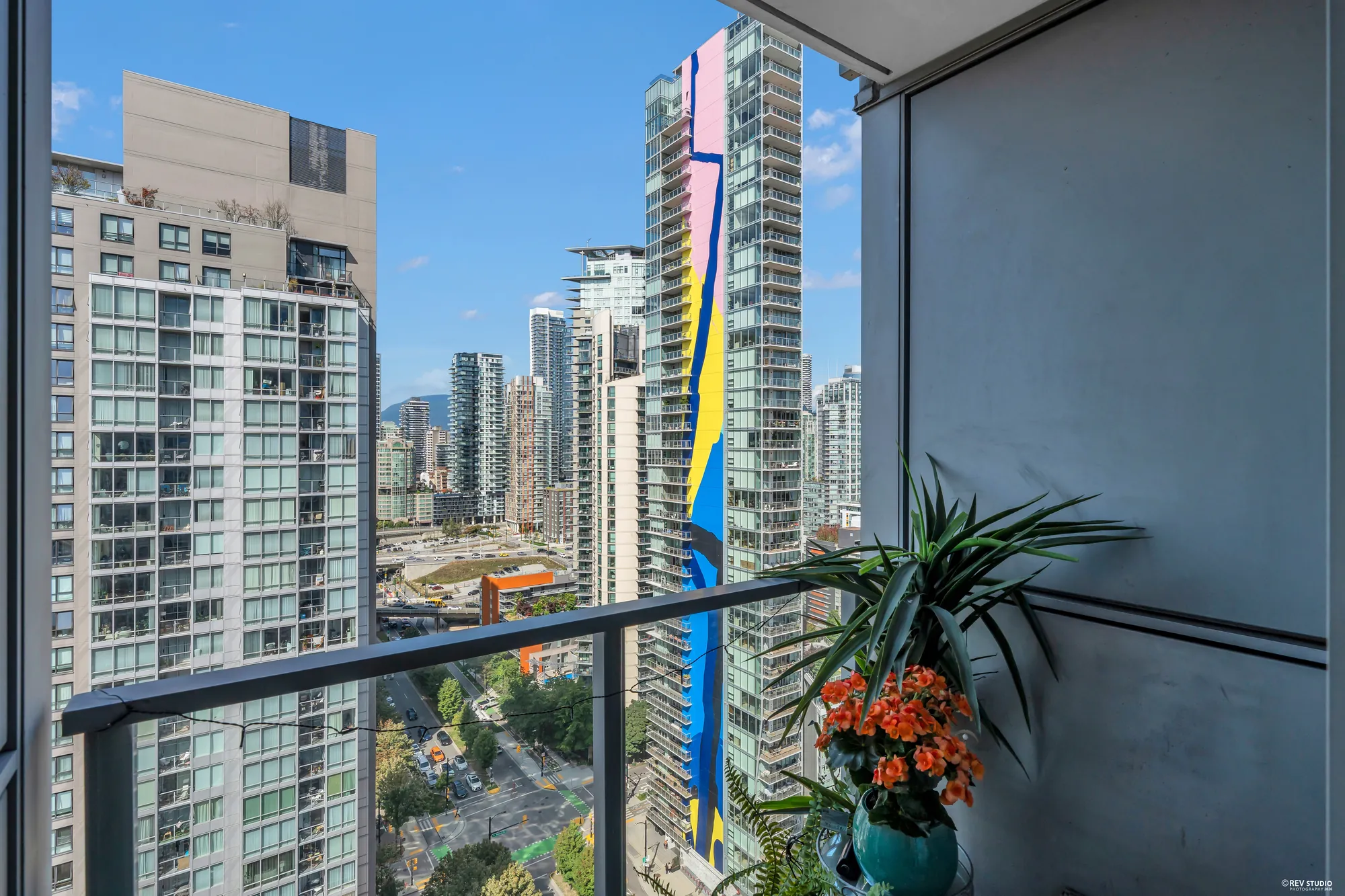 The covered balcony: a potted plant with orange flowers by the railing, the towers and the park beyond