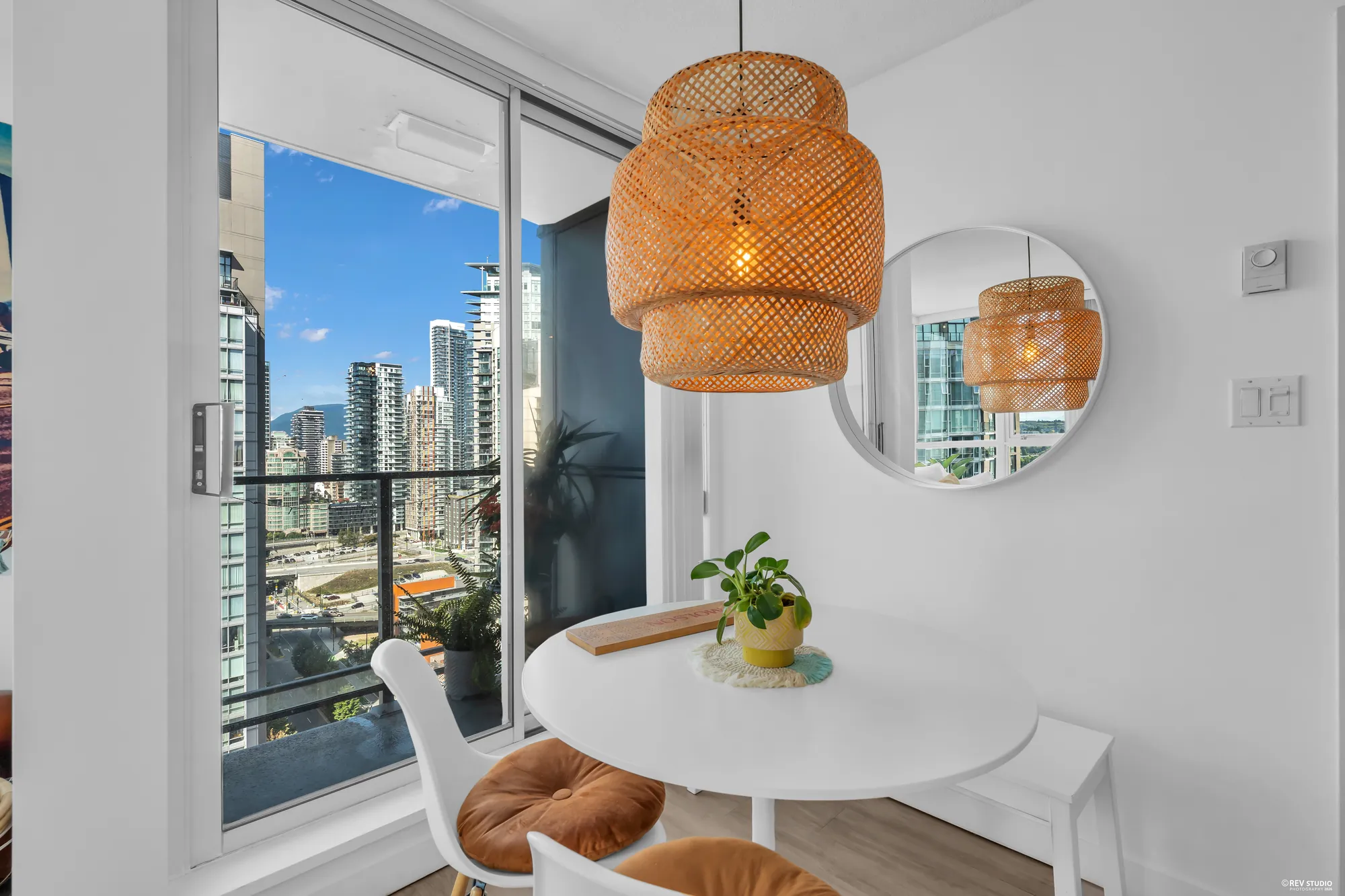 The dining table against the glass with the towers and the water below, the pendant above it