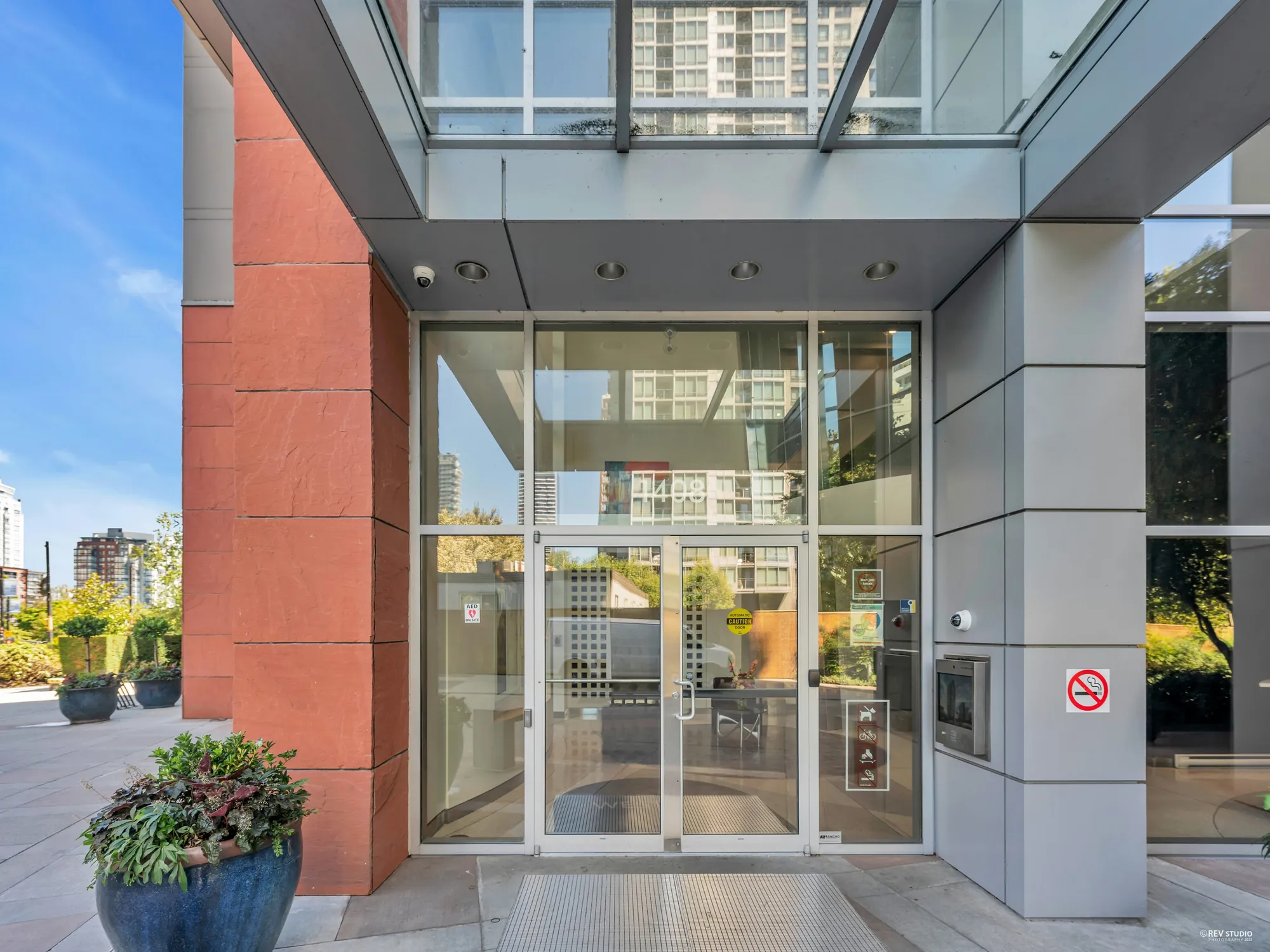 The entrance: glass doors under a canopy between red-brick piers, a planter beside them
