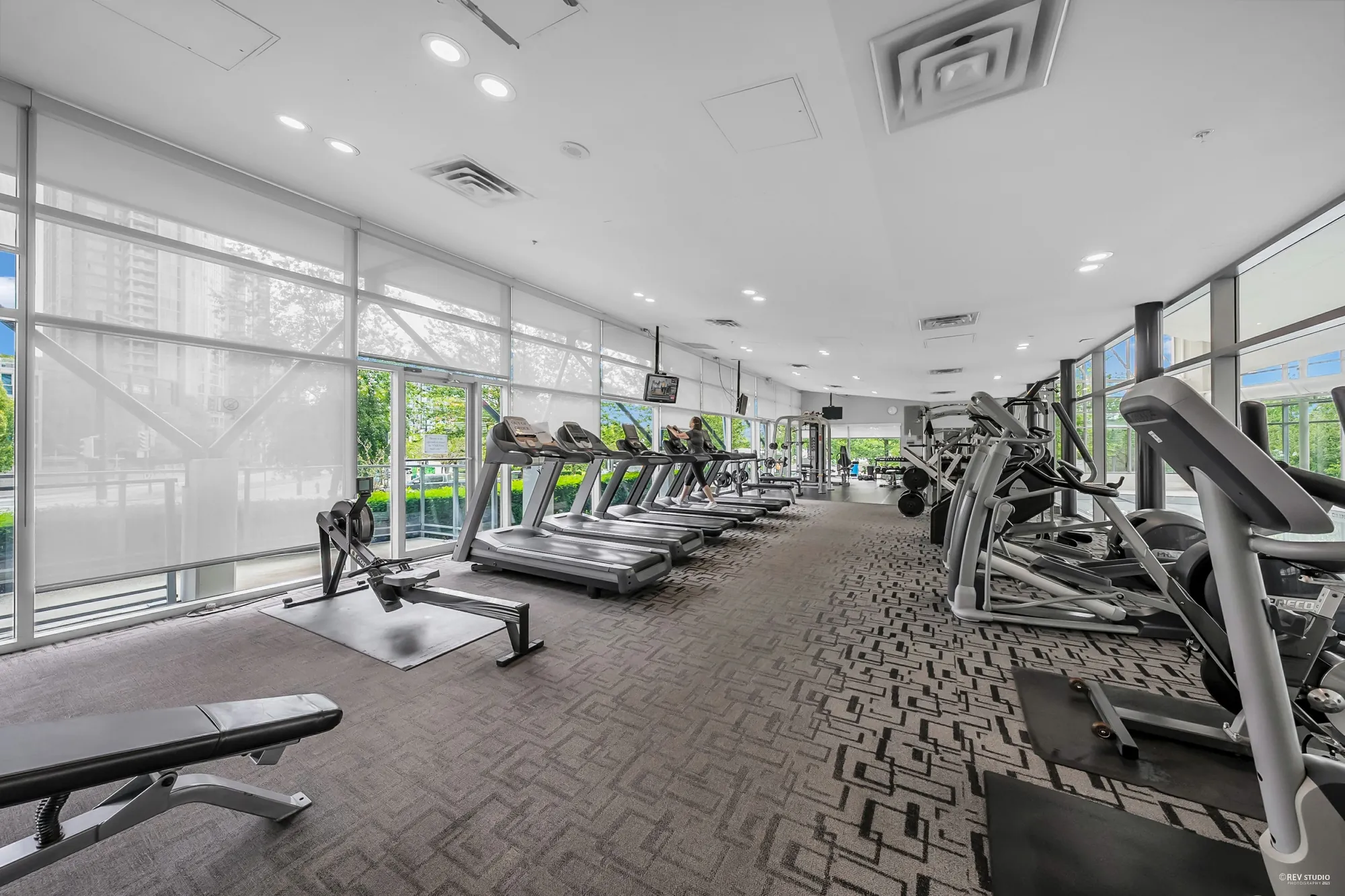 The fitness centre: treadmills and machines along a wall of glass, the pool beyond