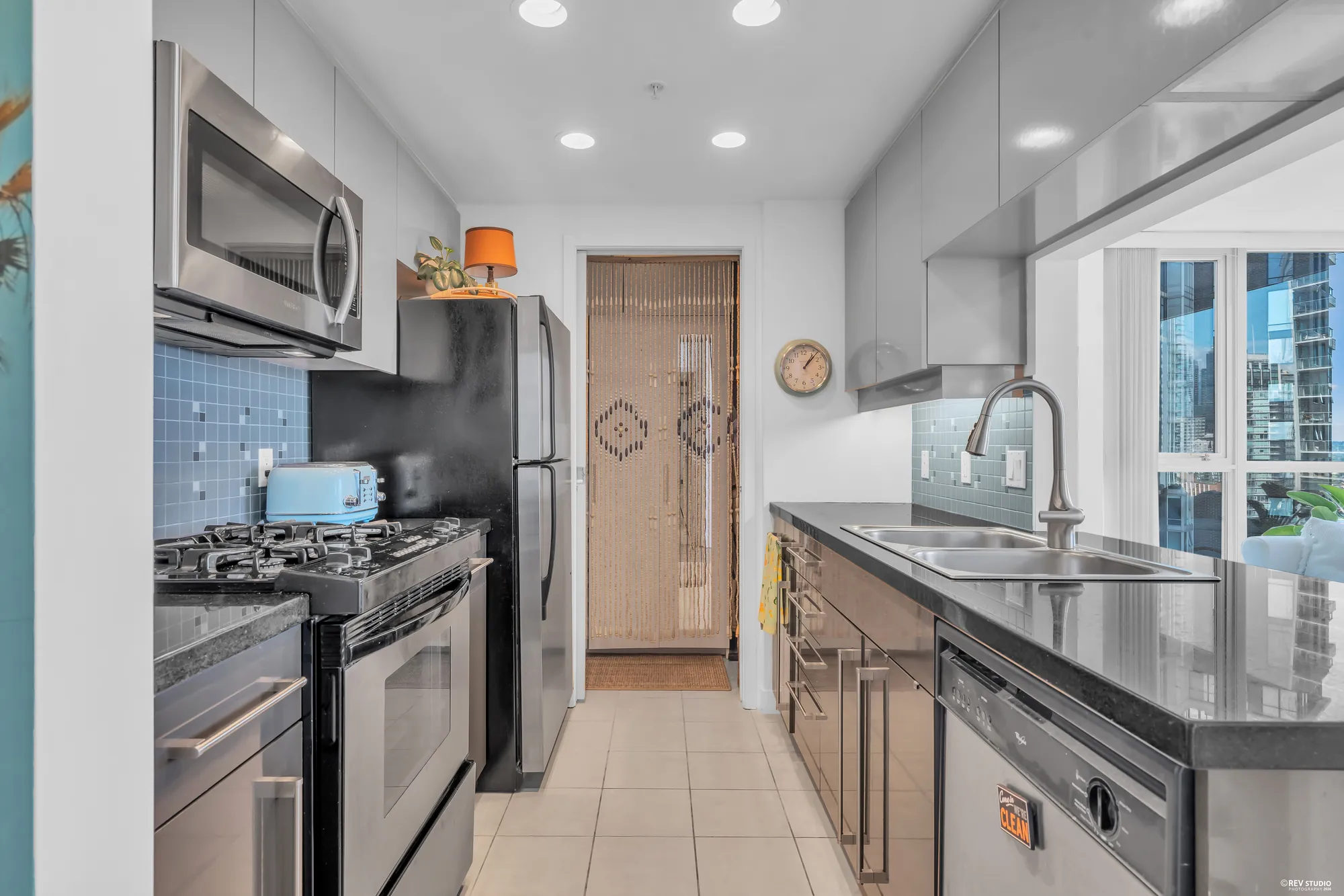 The kitchen: the gas range and microwave, the sink, the black granite counter, the window at the end