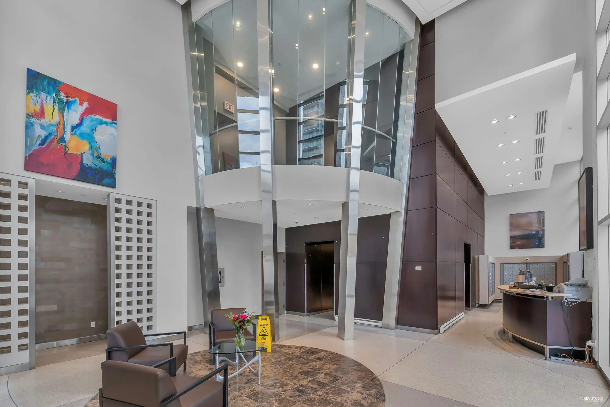 The lobby: a double-height space with a curved wall, leather chairs, the concierge desk and a painting