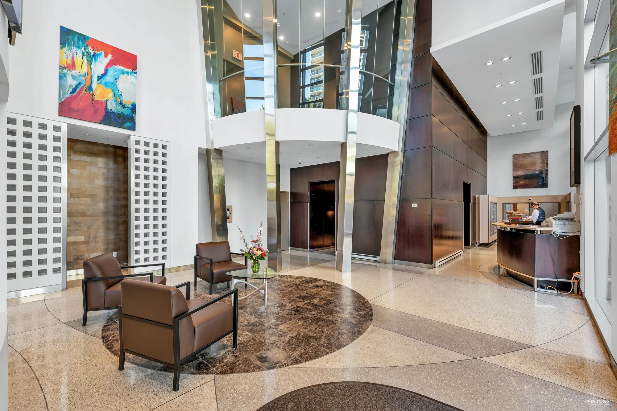 The lobby from the other side: the concierge desk, chairs on a patterned floor, the elevators beyond