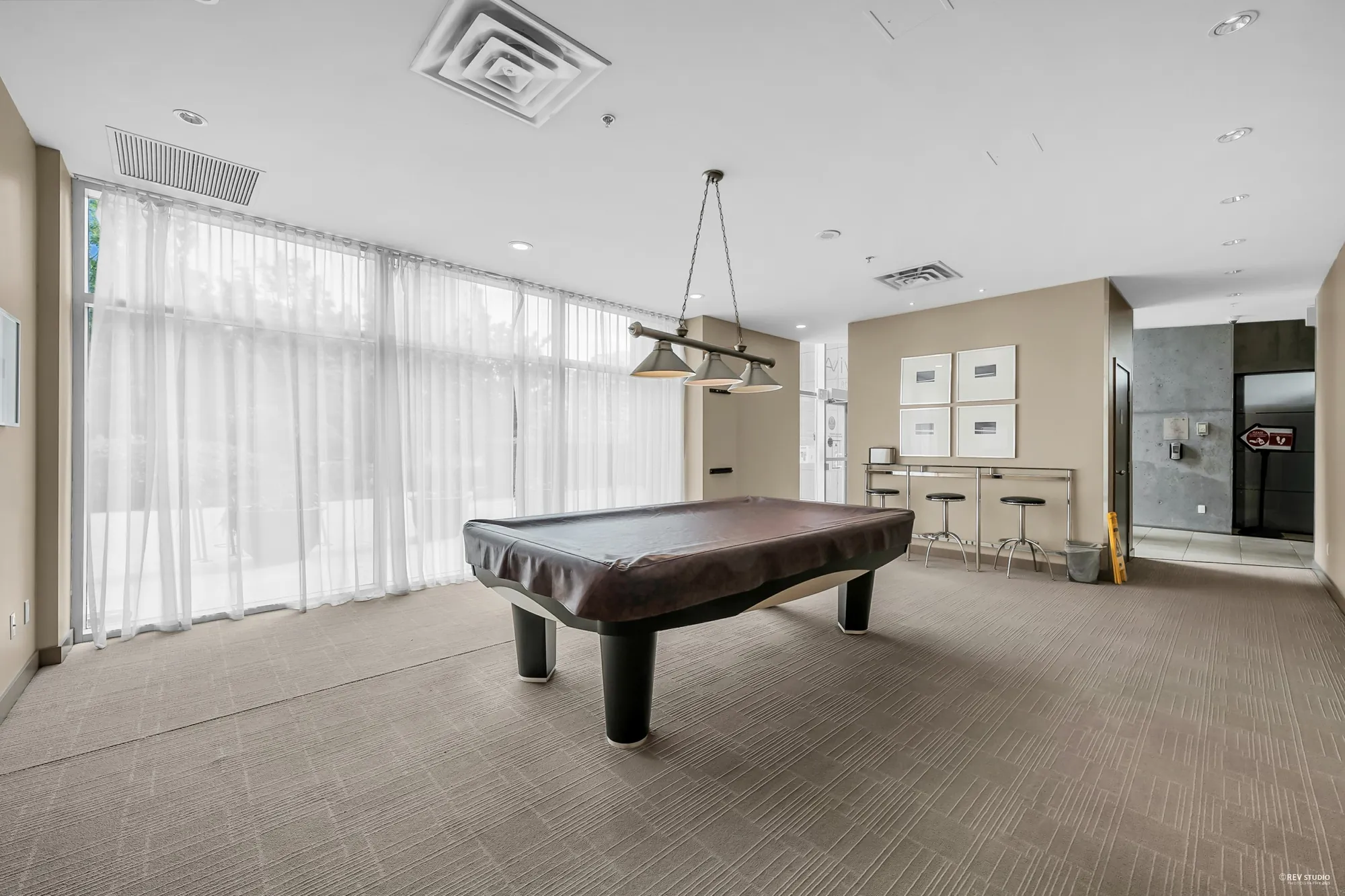 The lounge with a billiard table, a bar counter and stools, tall windows