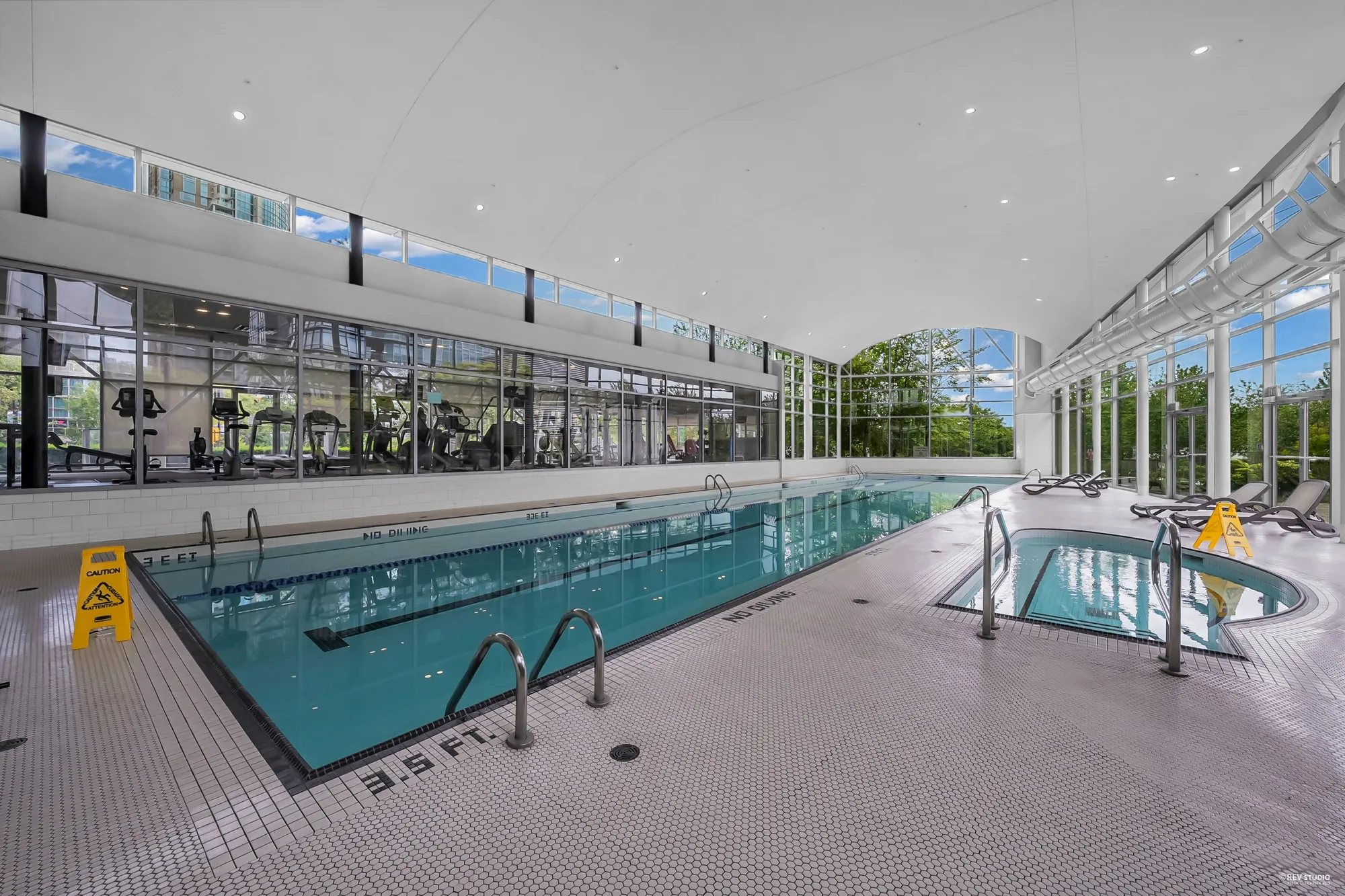 Club Viva's indoor pool under a glass roof, the hot tub beside it, the gym behind the glass