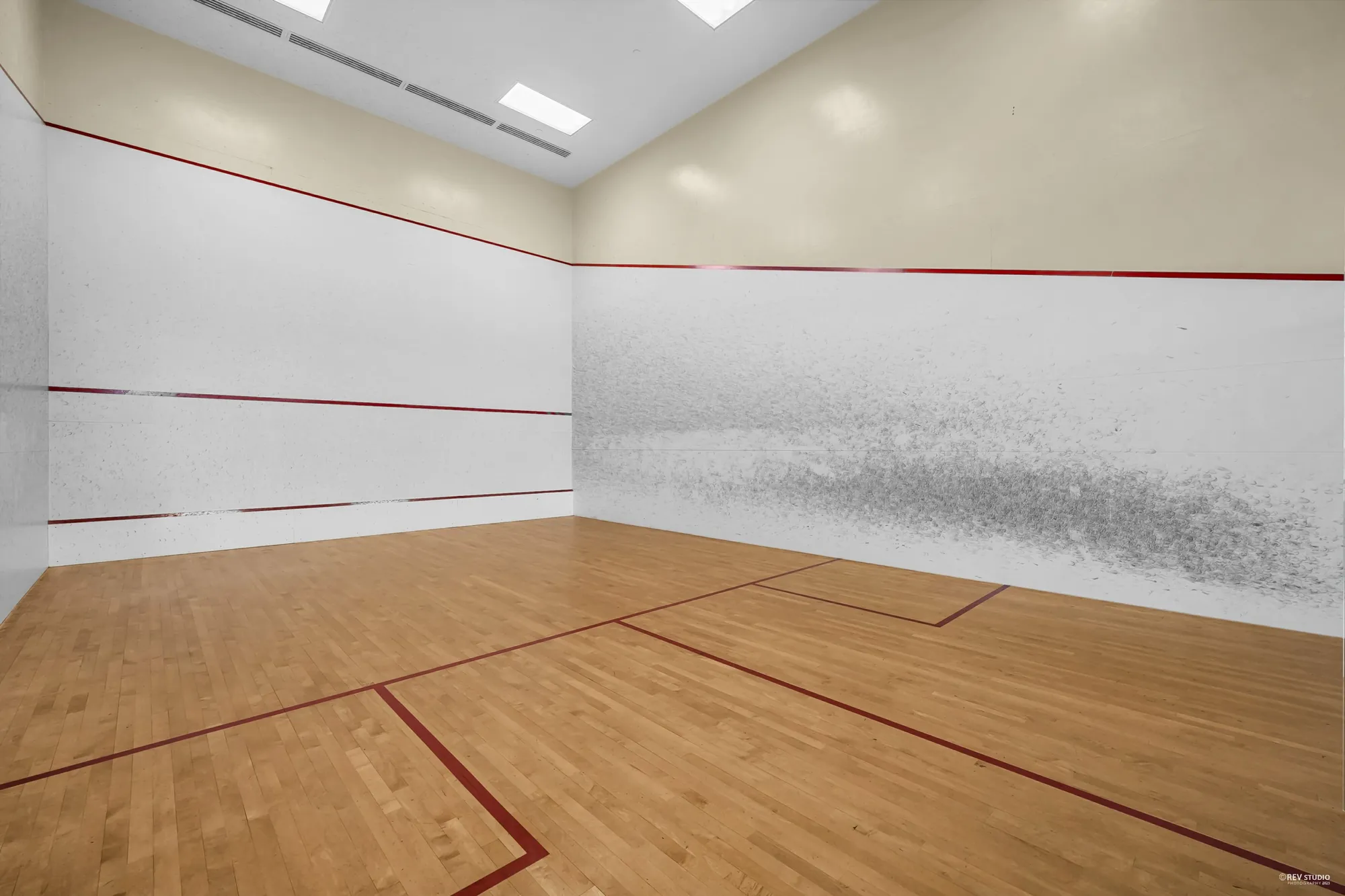 The squash court: white walls, a wooden floor with red lines
