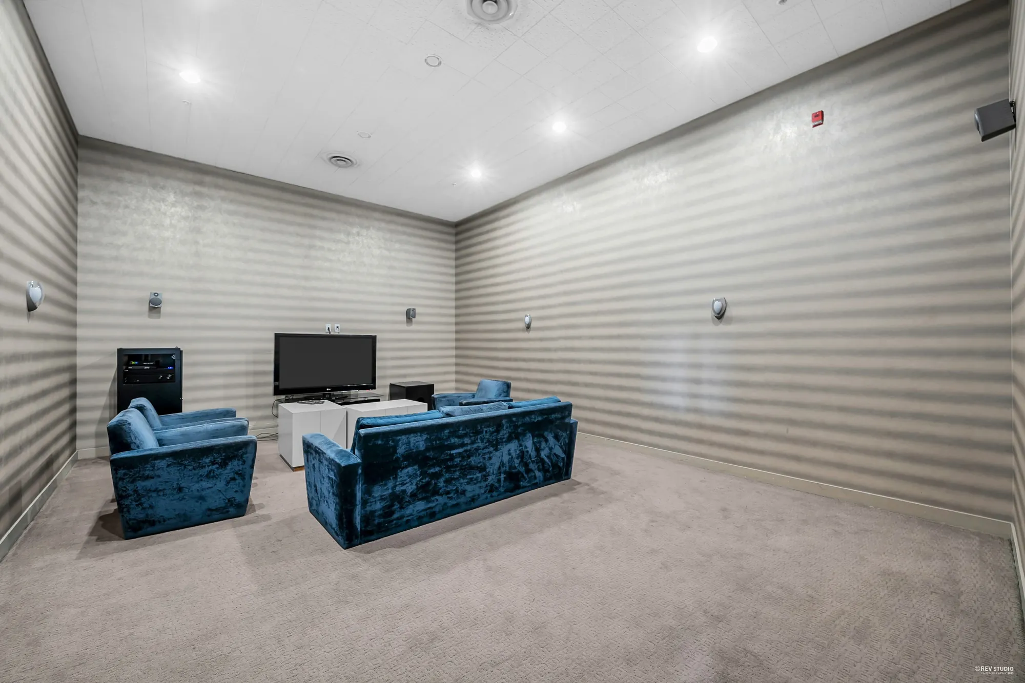 The television room: blue velvet sofas facing a screen, striped walls