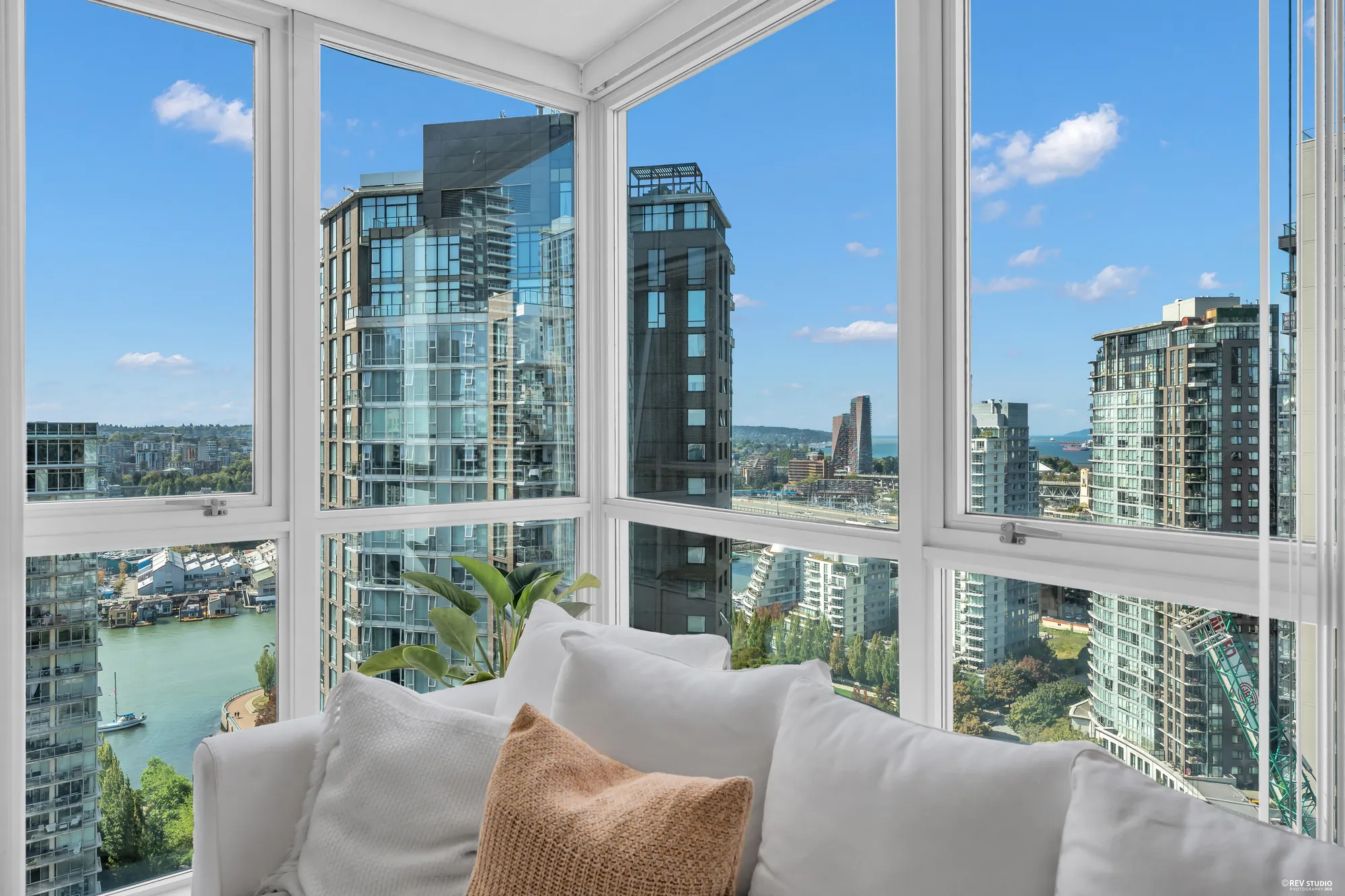 The corner of glass from the sofa: the towers across False Creek, the water and the seawall below